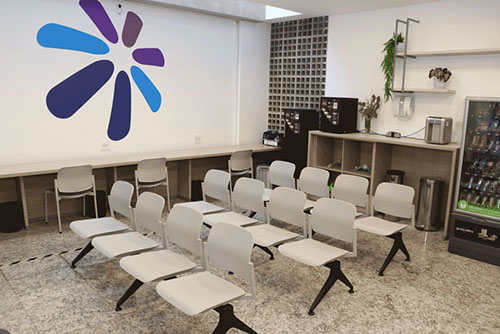 Recepção moderna e acolhedora da Clínica Sphera com recepcionista sorridente atendendo paciente, mostrando ambiente profissional e acessível